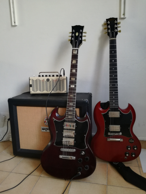 Guitare électrique CMI SG des années 1970, dotée de 3 micros, et posée à côté d'une Gibson SG à deux micros.